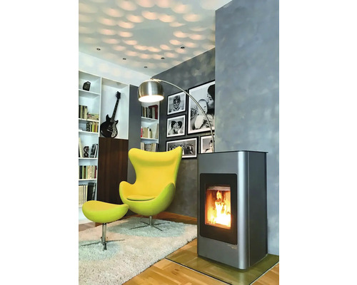 Obývací pokoj s kamny, křeslem, stojací lampou a knihovnou