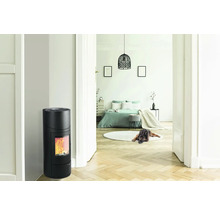 Interiér s černými kamny a výhledem do ložnice.