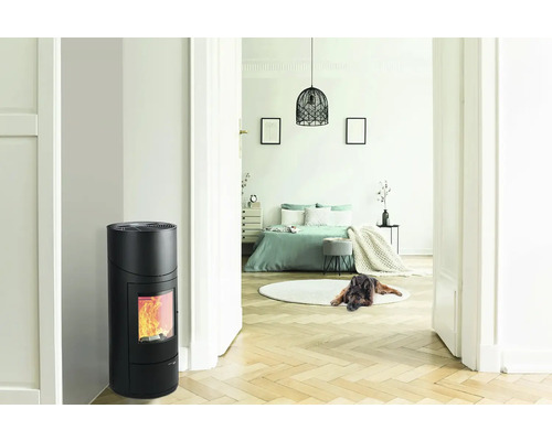 Interiér s černými kamny a výhledem do ložnice.