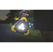 Osoba drží trojúhelníkové pracovní světlo s rukojetí