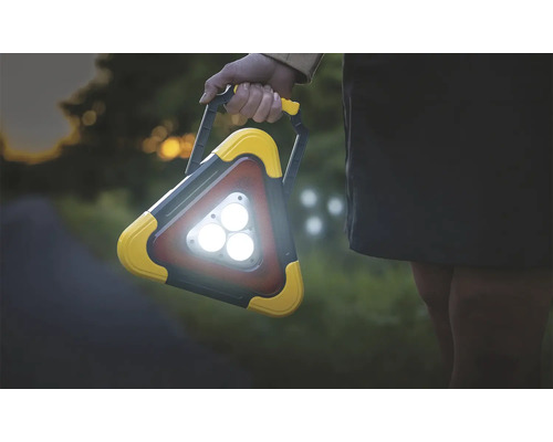 Osoba drží trojúhelníkové pracovní světlo s rukojetí