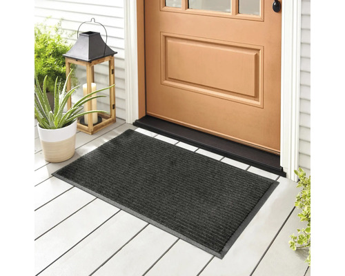 Šedá rohožka před vchodovými dveřmi na verandě s rostlinami a lucernou