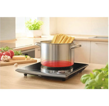 Nerezový hrnec se špagetami na indukční varné desce v kuchyni