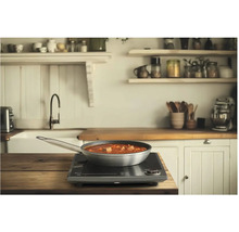 Pánev s jídlem na indukční varné desce v kuchyni