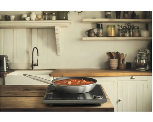 Pánev s jídlem na indukční varné desce v kuchyni