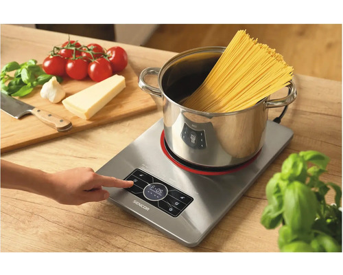 Indukční varná deska s hrncem, špagetami a přísadami pro přípravu pokrmů