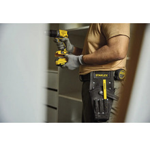 Řemeslník s akumulátorovým šroubovákem, pásem na nářadí a skládacím metrem staví skříň