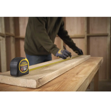 Řemeslník značí dřevěnou desku pomocí svinovacího metru Stanley Fatmax o délce 8 metrů na pracovním stole