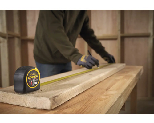 Řemeslník značí dřevěnou desku pomocí svinovacího metru Stanley Fatmax o délce 8 metrů na pracovním stole