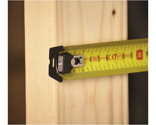 Žlutý svinovací metr s klipem na kusu dřeva