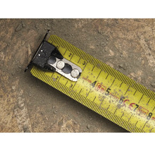 Žlutý svinovací metr s kovovými prvky na povrchu