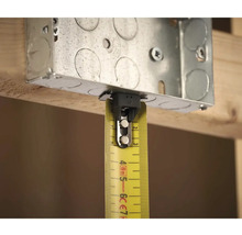 Kovová instalační krabice se žlutým svinovacím metrem pro měření na dřevěné konstrukci