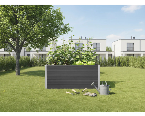 Zvýšený záhon na zahradě se zeleninou, zahradním nářadím a konví