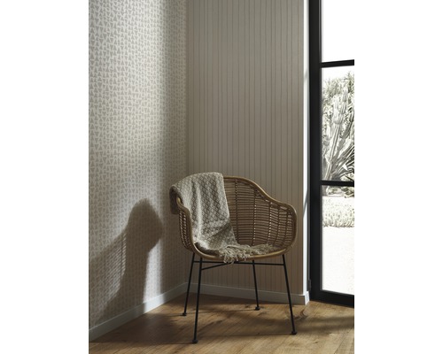 Pokoj s tapetami se vzory a pruhy, ratanovým křeslem a vlněnou dekou