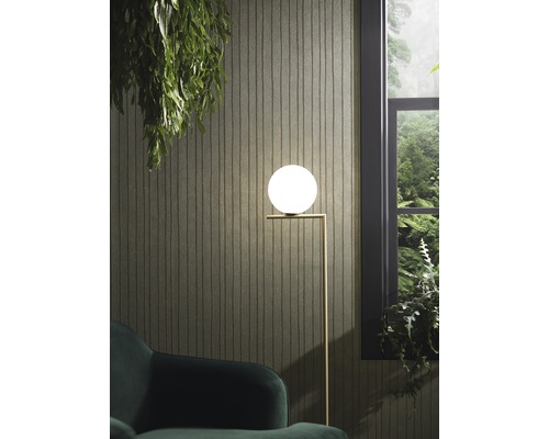 Scéna se stojací lampou s kulovitým stínidlem, křeslem a výhledem z okna na bujnou zeleň