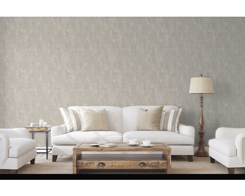 Obývací pokoj s pohovkou, křeslem, stolem a stojací lampou před decentní vzorovanou tapetou.