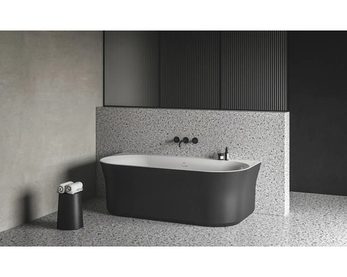 Volně stojící vana v moderní koupelně s teracovou podlahou a obkladem stěn