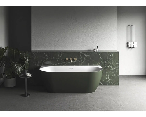 Volně stojící vana v koupelně s rostlinami a držákem na ručníky.