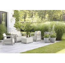 Zahradní nábytek s pohovkou, křeslem a stolem na terase se zeleným trávníkem a rostlinami.