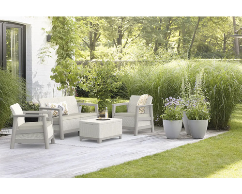 Zahradní nábytek s pohovkou, křeslem a stolem na terase se zeleným trávníkem a rostlinami.