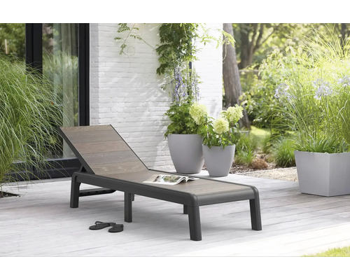 Zahradní scéna s zahradním lehátkem, rostlinami v květináčích a botami