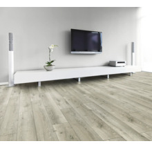 Obývací pokoj se světlou dřevěnou laminátovou podlahou, bílou nízkou skříňkou, televizí a reproduktory