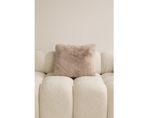 Čtvercový dekorativní polštář se vzhledem kožešiny na pohovce.