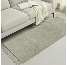 Šedý běhoun se střapci vedle pohovky s knihou