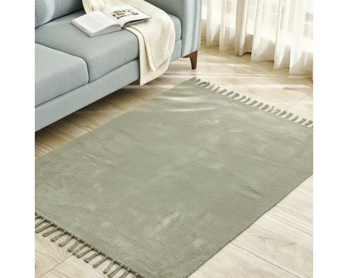 Čtvercový koberec s třásněmi vedle pohovky na dřevěné podlaze