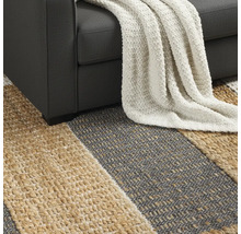 Detailní pohled na pruhovaný koberec pod pohovkou s dekou.