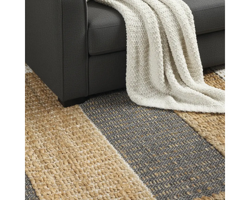 Detailní pohled na pruhovaný koberec pod pohovkou s dekou.