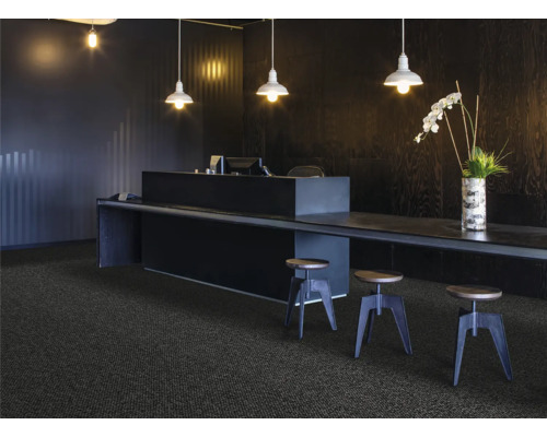 Recepce s kobercem, stolem a barovými stoličkami pod závěsnými lampami