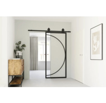 Interiér chodby s posuvnými skleněnými a kovovými dveřmi s kruhovým designem, dřevěnou skříní s rostlinou a zarámovaným obrazem na stěně