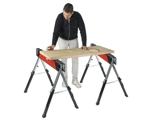 Řemeslník brousí dřevěnou desku na dvou kozech