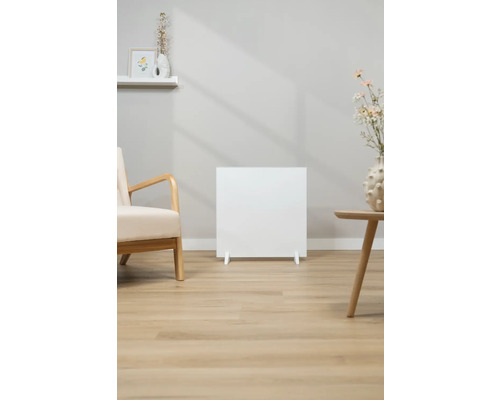 Bílý radiátor v obývacím pokoji s křeslem a stolem