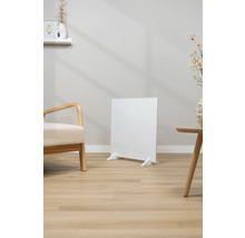 Bílý infračervený ohřívač stojí v světlém obývacím pokoji.