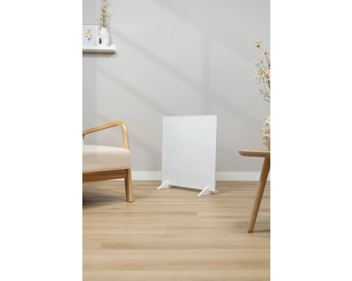 Bílý infračervený ohřívač stojí v světlém obývacím pokoji.