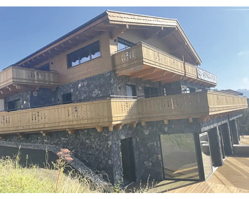 Vícepodlažní dům s dřevěným obkladem, kamenným zdivem a balkony