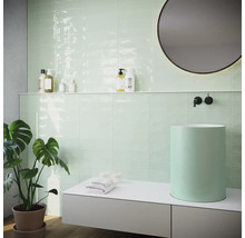 Moderní koupelna s mátově zelenými obklady, umyvadlem na desku a kulatým zrcadlem