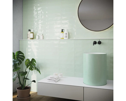 Moderní koupelna s mátově zelenými obklady, umyvadlem na desku a kulatým zrcadlem