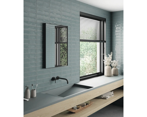 Světlá koupelna s umyvadlem, zrcadlem, oknem a obklady