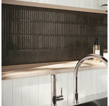 Nástěnná dekorace s podlouhlými, tmavými dlaždicemi a armaturou