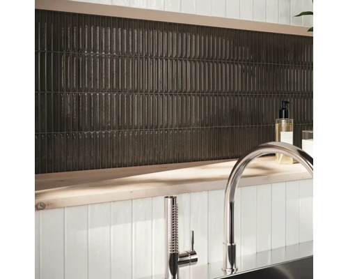 Nástěnná dekorace s podlouhlými, tmavými dlaždicemi a armaturou