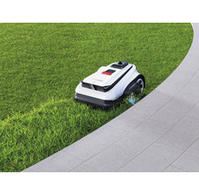 Robotická sekačka na trávníku vedle dlážděné cesty