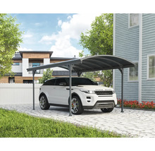 Auto pod přístřeškem pro auto na dlážděné příjezdové cestě před domem