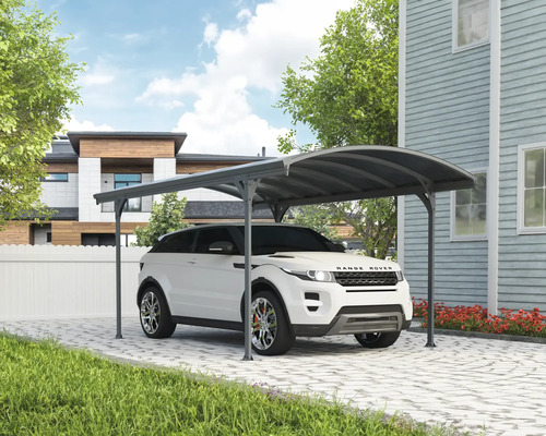 Auto pod přístřeškem pro auto na dlážděné příjezdové cestě před domem