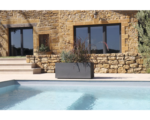 Šedý květináč s rostlinami vedle bazénu před domem
