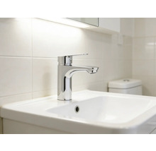 Umyvadlo s baterií ve světlé koupelně.