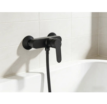 Černá vanová baterie se sprchovou hadicí na obložené stěně nad vanou