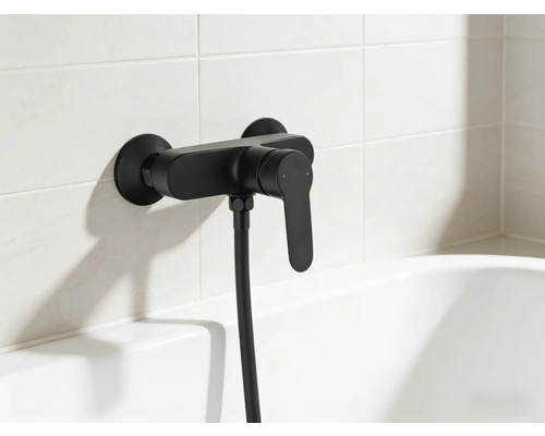 Černá vanová baterie se sprchovou hadicí na obložené stěně nad vanou
